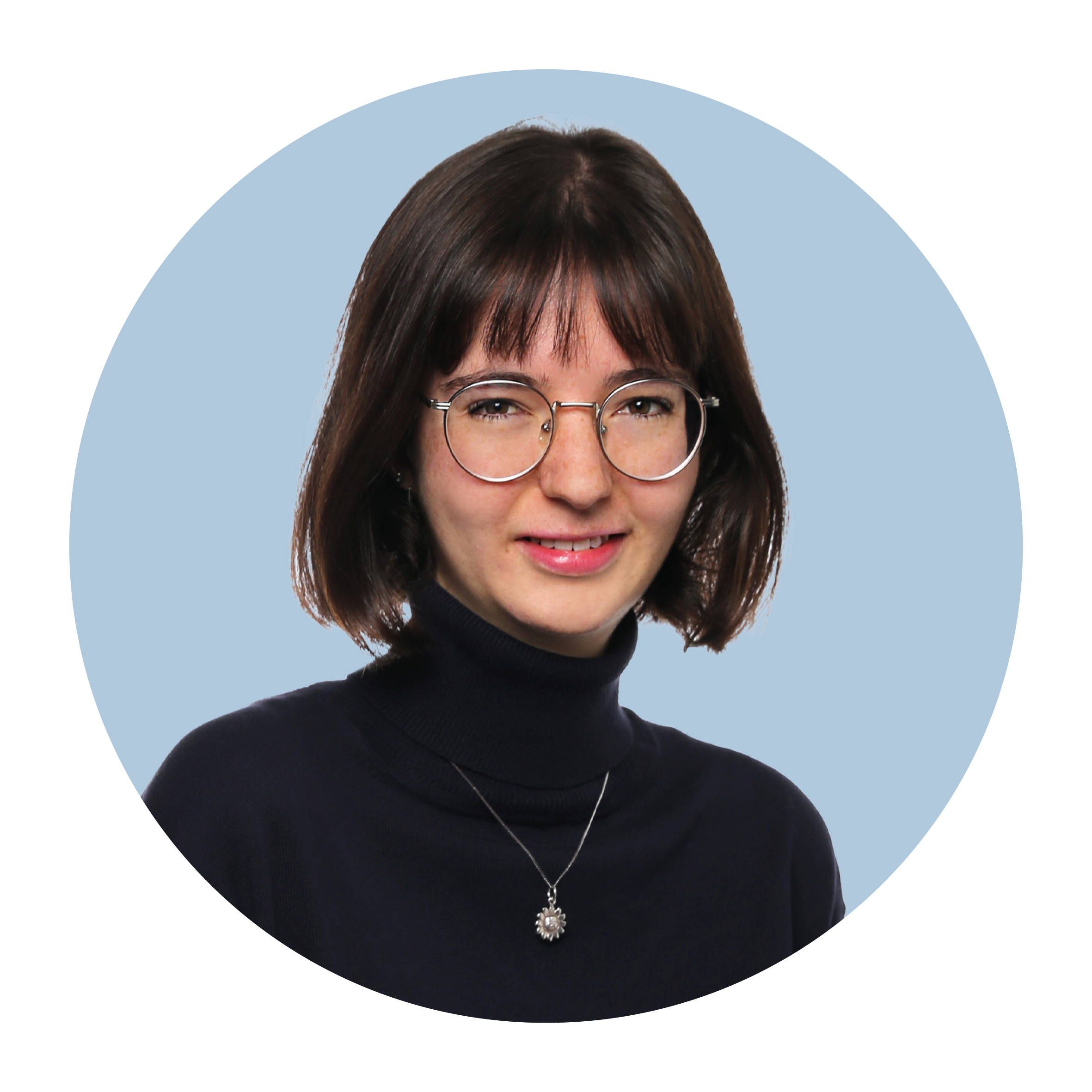 Portrait of Emilia Senn, a white woman with shoulder-length dark brown hair worn loose, wearing a black top and glasses, smiling broadly.