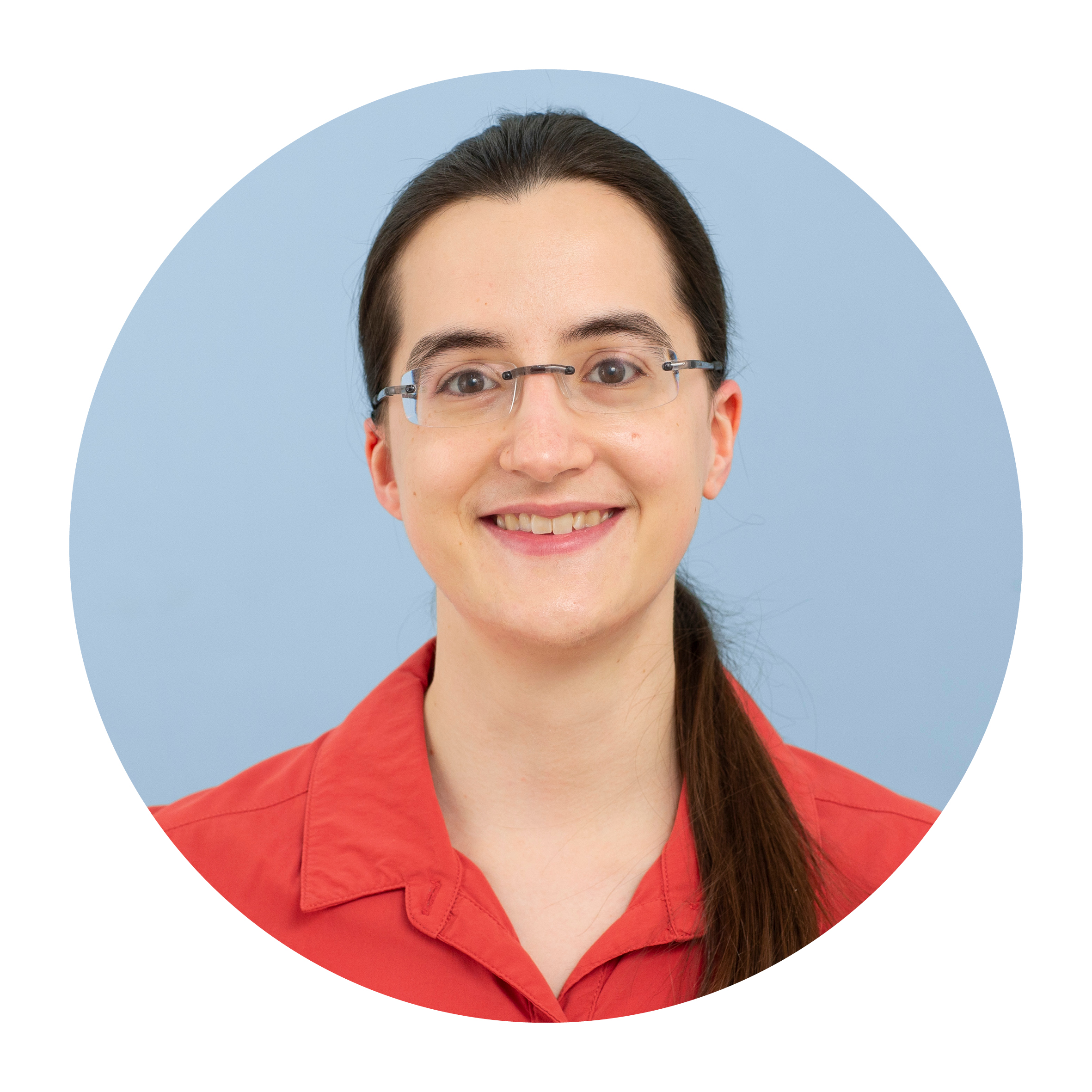 Portrait of Hanna Marti, a white woman with long brown hair tied back, wearing a red top and glasses, smiling broadly.