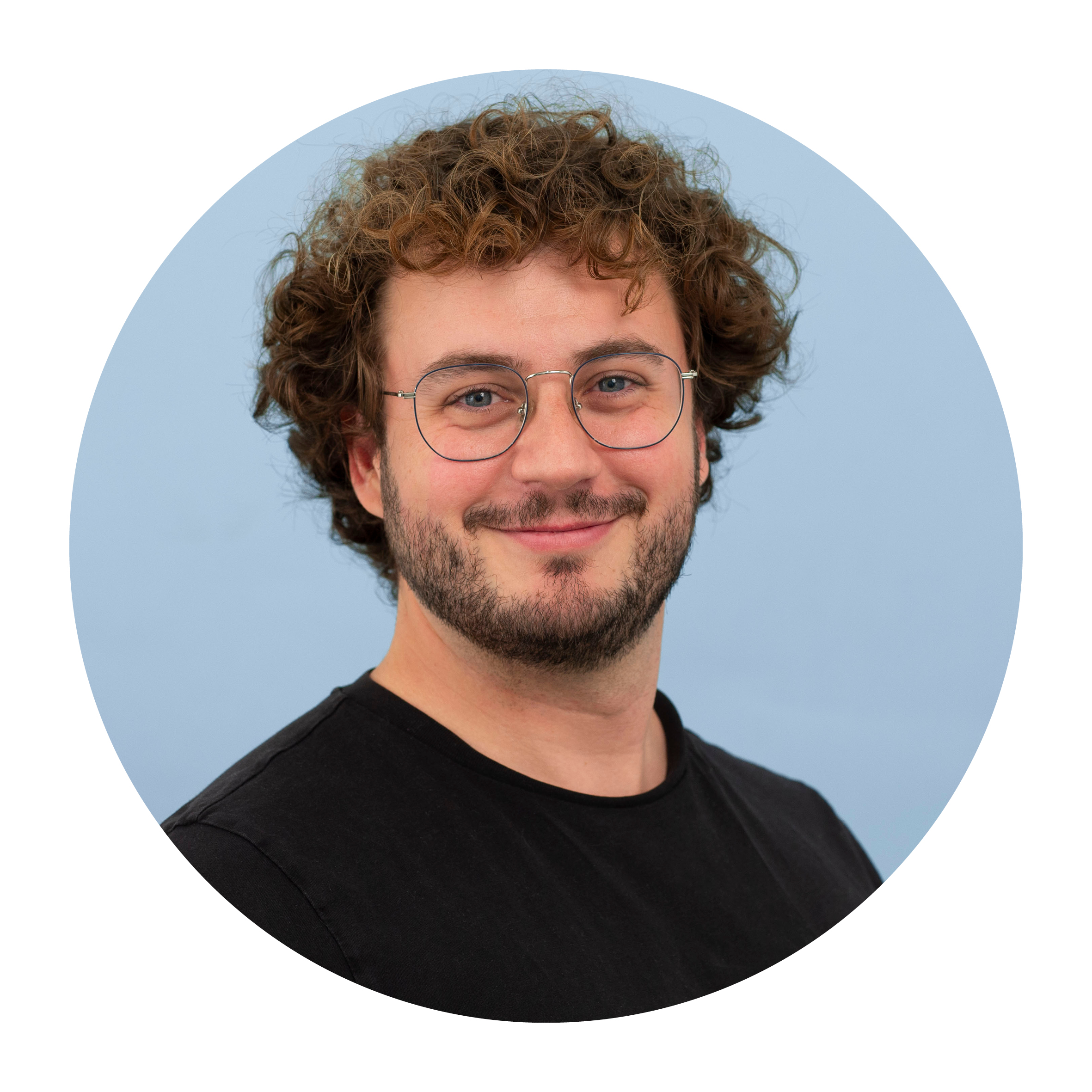 Portrait of Enrique Rayo, a white man with short brown hair, wearing a black top and glasses, smiling.