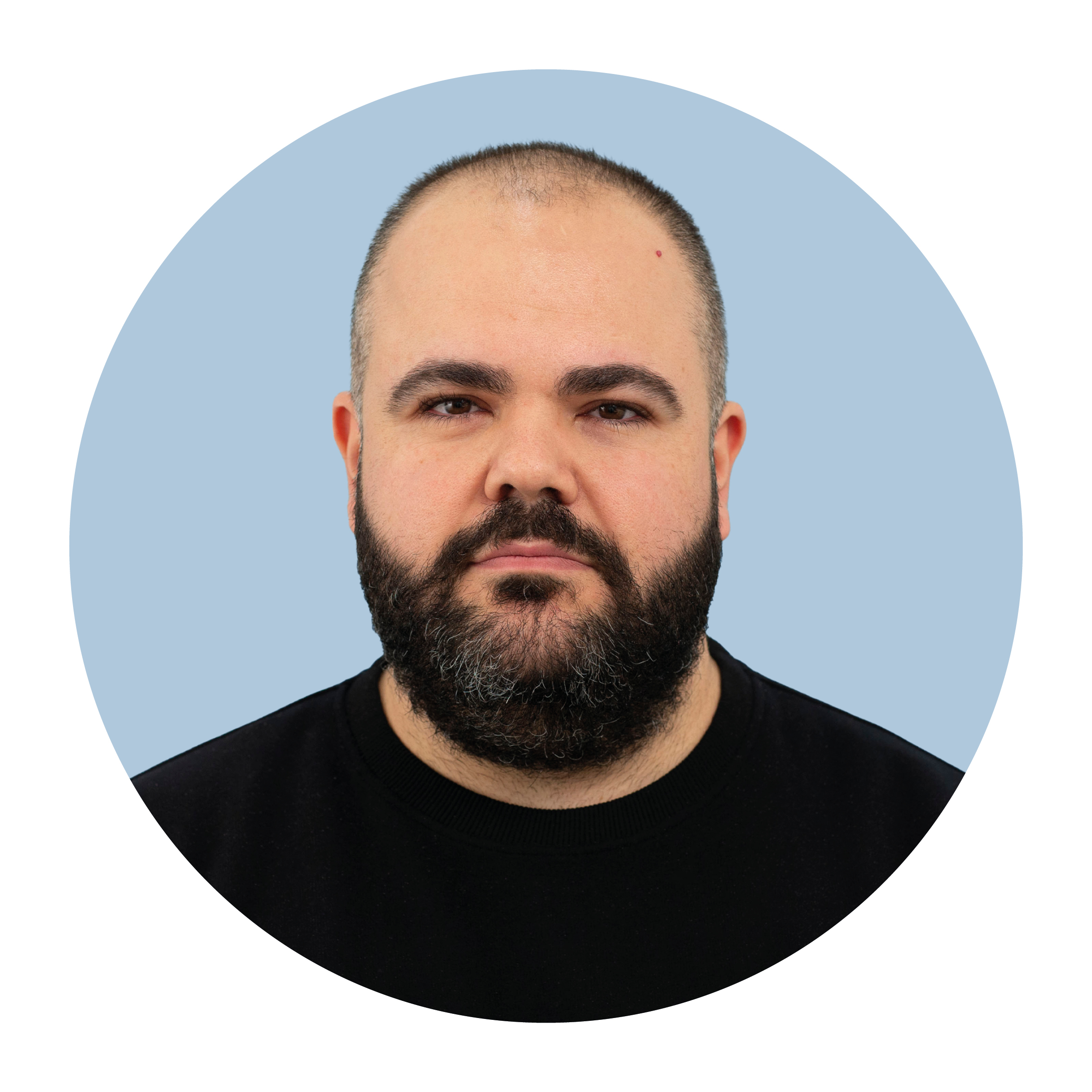 Portrait of Efe Altuntas, a white man with very short black hair and a full black beard, wearing a black top and smiling.